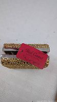 Top and side view of gold sparkly Red Carpet Collection clutch showing texture and metallic frame with chain inside.