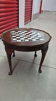Full view of the vintage wooden oval side table displaying the chess board inlay on top and four curved legs.