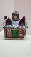 Front view of Tiffany Gallery Xmas Lighthouse stained glass house showing snow-covered roof, green door, and colorful windows.