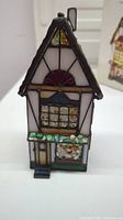 Stained glass lighthouse showing detailed panels, floral and geometric patterns, door and window details.