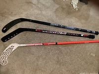 Image showing all three ball hockey sticks laid side by side, highlighting different blade styles and shaft colors.