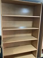 Front view of one light wood bookcase showing four adjustable shelves.