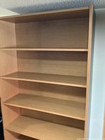 Wooden bookcase with five adjustable shelves in light wood finish, shown empty from a frontal angle.