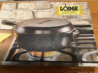 Front view of boxed Lodge cast iron pan showing product on gas stove.