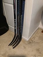 Photo showing blade ends of five hockey sticks clustered together, various brands visible such as CCM, Bauer, Sherwood