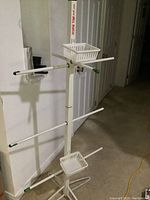 Full view of white metal hockey equipment drying stand with rods and baskets.