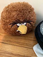 Brown round Angry Birds character pillow with fur texture and detailed face including eyes, eyebrows, beak, and tooth.