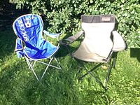 Both folding chairs side by side outdoors on grass, blue soccer-themed and beige Coleman chair.