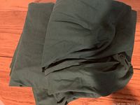 Green bedsheet folded on wooden floor showing fabric color and texture