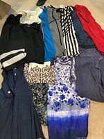 Full view of twelve assorted ladies summer dresses laid out, showing various colors, patterns, and styles.