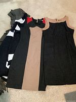 Photo showing seven summer dresses including color block and solid color dresses laid on a floor.