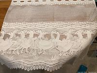 Close-up photo showing intricate crochet detail and duck pattern with scalloped edge
