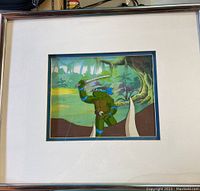 Full framed view showing the animation cell with forest background and Leonardo character, matted and framed in silver frame.