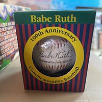 View of Babe Ruth commemorative baseball inside original packaging showing printed signature and 100th anniversary label.