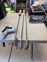 Three golf clubs including Ping Ross putter, 52 degree sand wedge, and an iron on a table