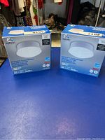 Two new boxed retrofit flush mount ceiling fixtures by Enormic with product info visible.