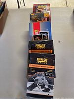 Stack of sports card boxes including Topps 1994 baseball and Pinnacle 1996-97 hockey cards on a table.