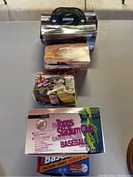 Shows four boxes of baseball card packs stacked, including a Topps Stadium Club box and others, all resting on a table.