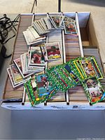 Photo showing football cards with vibrant green-bordered designs and several white-border cards in used condition.