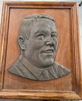 Front view of the bronze portrait sculpture mounted on wood frame, showing overall condition and frame details.