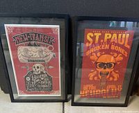 Two framed music posters side by side on a surface showing full artworks and frames.