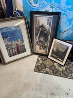 Three framed prints: Michael Godard $100 bill with octopus, black and white Yosemite, and architectural cityscape.