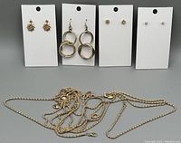 Photo of four pairs of gold-tone earrings on display cards and two gold-tone necklaces placed below