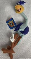 Multicolor Roadrunner plush toy from Looney Tunes featuring original tags, positioned on a fabric surface.