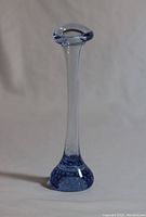 Photo showing full view of vintage blue bubbled glass vase with long slender neck and rounded flared rim, standing upright on neutral background.