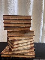Stack of antique books with visible worn edges and marbled cover on bottom book