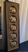 Full view of the tall, narrow framed textile art with five embroidered elephants stacked vertically.