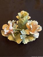 View of porcelain candle holder showing large roses, smaller blue flowers, and green leaves