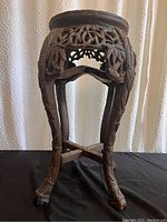 Front view of the carved wooden stand with floral and bamboo leaf patterns. Missing marble top. Wear and repairs needed.