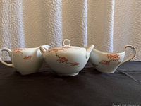 Front view of the creamer, covered dish with lid, and small bowl showcasing the hand-painted maple pattern and gold accented handles.