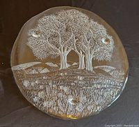 Top-down view of round glass plate with embossed trees and flowers