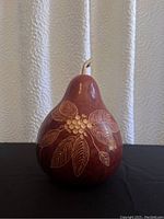 Front view of hand painted and carved gourd bowl showing detailed leaf and berry design.