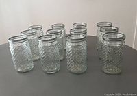 Top view of twelve clear hobnail glass jar vases arranged on a table showing textured hobnail pattern and cylindrical shape.
