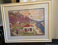 Frontal view of framed print showing island sunset artwork with houses, palm trees, and river under sunset sky.