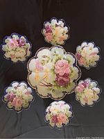 Top-down view of large bowl surrounded by 6 smaller companion bowls, all with cobalt blue scalloped edges and hand-painted flower design with gold accents.