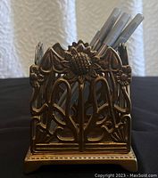 Front view of the vintage brass pen holder showing sunflower and vine pattern with pens inside.