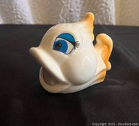 Front side view of ceramic goldfish sponge holder showing facial features, open mouth, blue eye with long eyelashes, cream-white and orange color accents.