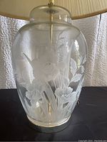 Close-up of clear glass lamp base with etched floral and leaf design.