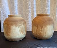 Front view of two rounded wooden vases showing natural wood grain and smooth finish.
