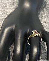Side-angle view of ring on black display hand showing twisted band and gemstone cluster