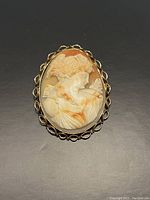 Front view of one large cameo brooch showing female profile in carved shell with yellow gold frame