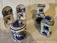 Photo showing the set of blue and white ceramics including lidded Delftware canister, ginger jar, vase, and hanging candleholders, all with nautical ship designs.