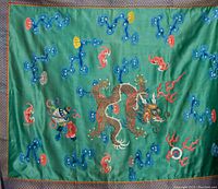 Full view of green silk hanging with embroidered dragon and multicolored cloud designs bordered by gold and blue brocade.