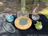 Lot displayed outside on black cloth, showing all pieces including glass dome on wooden Lazy Susan with marble insert, glass bowl with colored marbles and beads, and three smaller dishes.
