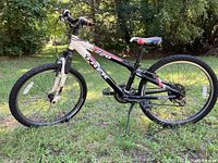 Side view of black, white, and red Trek MT 200 boys mountain bike on grass showing full bike profile
