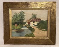 Full view of signed E.E. Swannell village landscape oil painting in original rustic gold-washed wooden frame.
